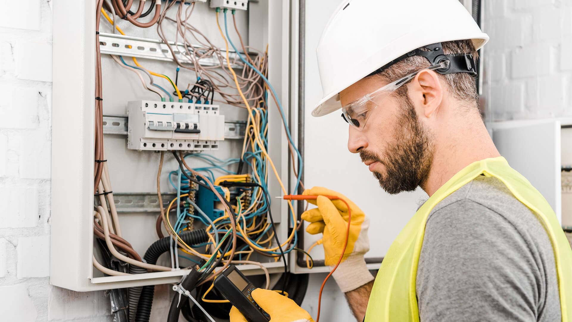 Electrician using test equipment at an open electrical panel